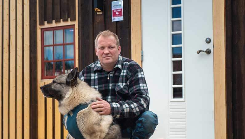 Mann og hund foran hus med Verisure alarm