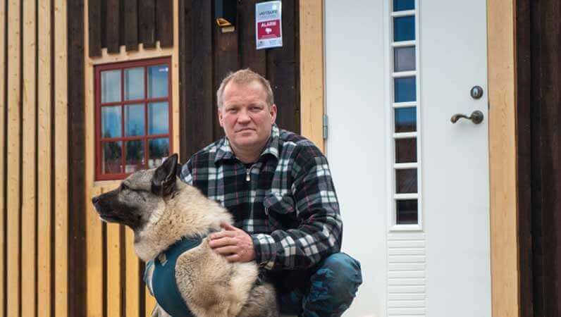 Mann og hund foran hus med Verisure alarm