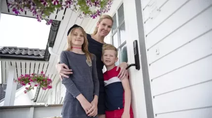 Familie foran dør med alarm og dørlås Familie foran dør med alarm og dørlås