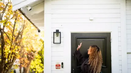 kvinne vinker til kamera ved inngangsdør
