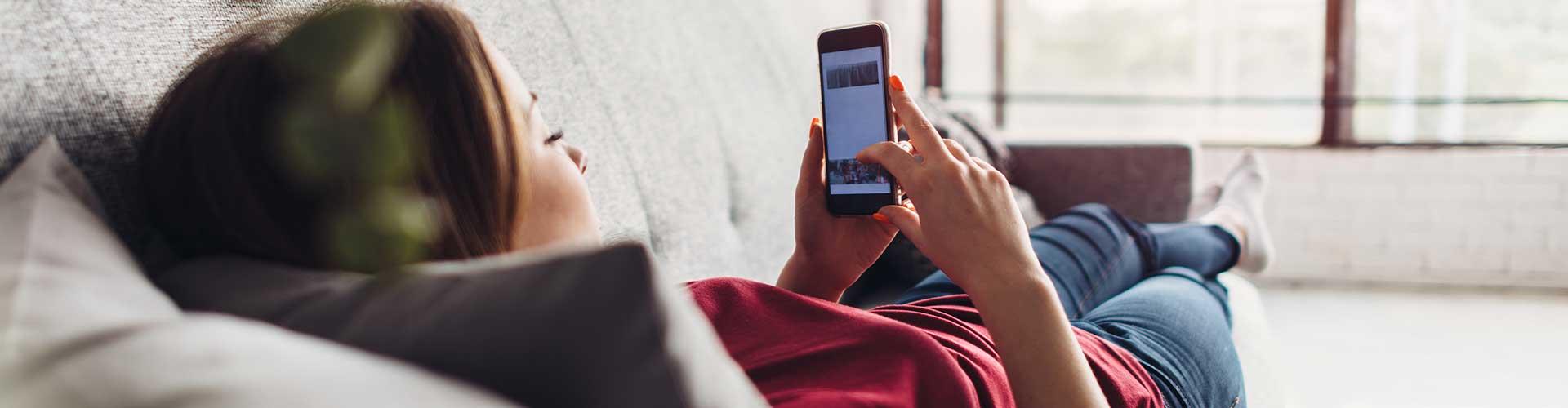 Jente ser på Verisure Cameras app fra sofaen