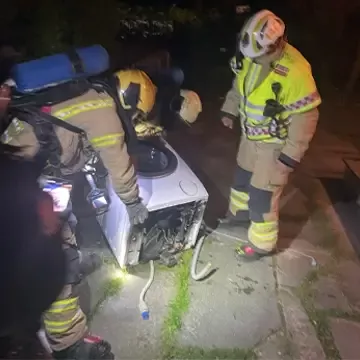 Brannvesen bærer ut brent vaskemaskin