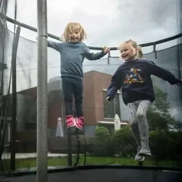 Glade og trygge barn på trampoline foran innbruddssikret bolig